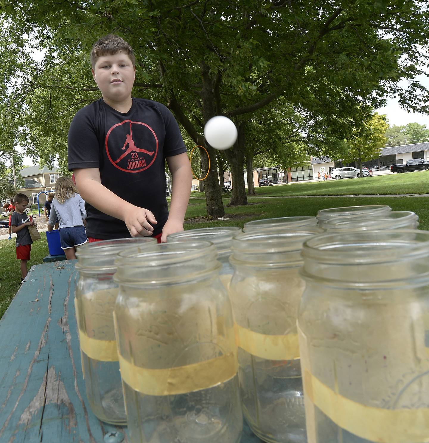 Carter Wheeler tosses a ping pong ball into jars Wednesday, July 27, 2022, at the Ottawa City Recreation game carnival in Rigden Park.
