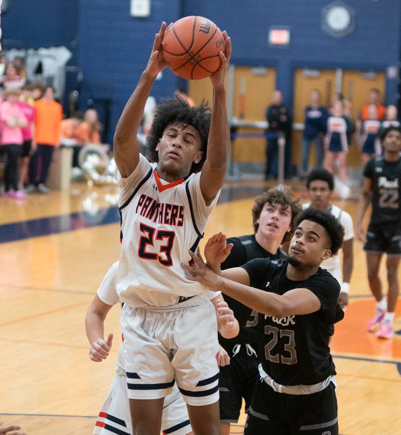Oswego’s Dasean Patton (left) rebounds the ball against Oswego East's Torrin Ross (right) during a basketball game at Oswego High School on Tuesday, Dec 12, 2023.