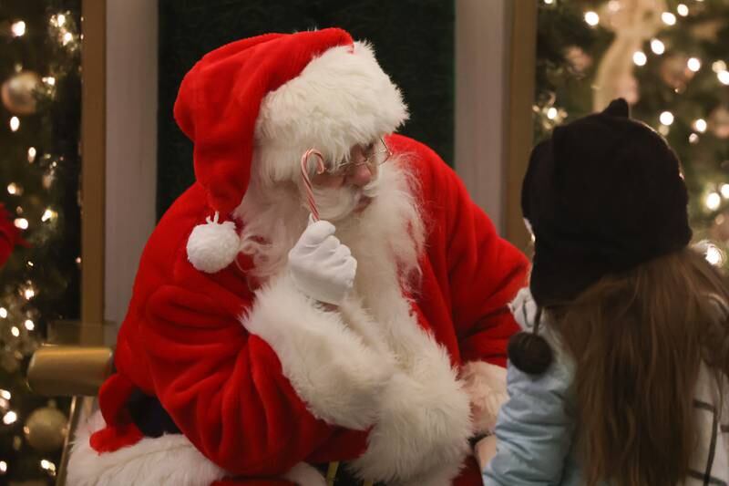 Santa gives a candy cane to a little girl at New Lenox’s Christmas in the Commons.