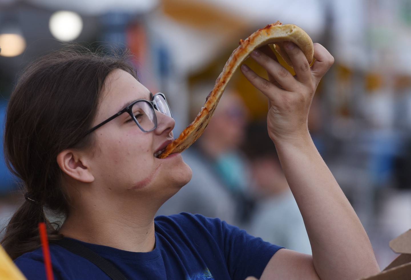 Amber Sytsma of South Elgin enjoys a sliice of pizza during the Kane County Fair on Thursday, July 18, 2024 in St. Charles.