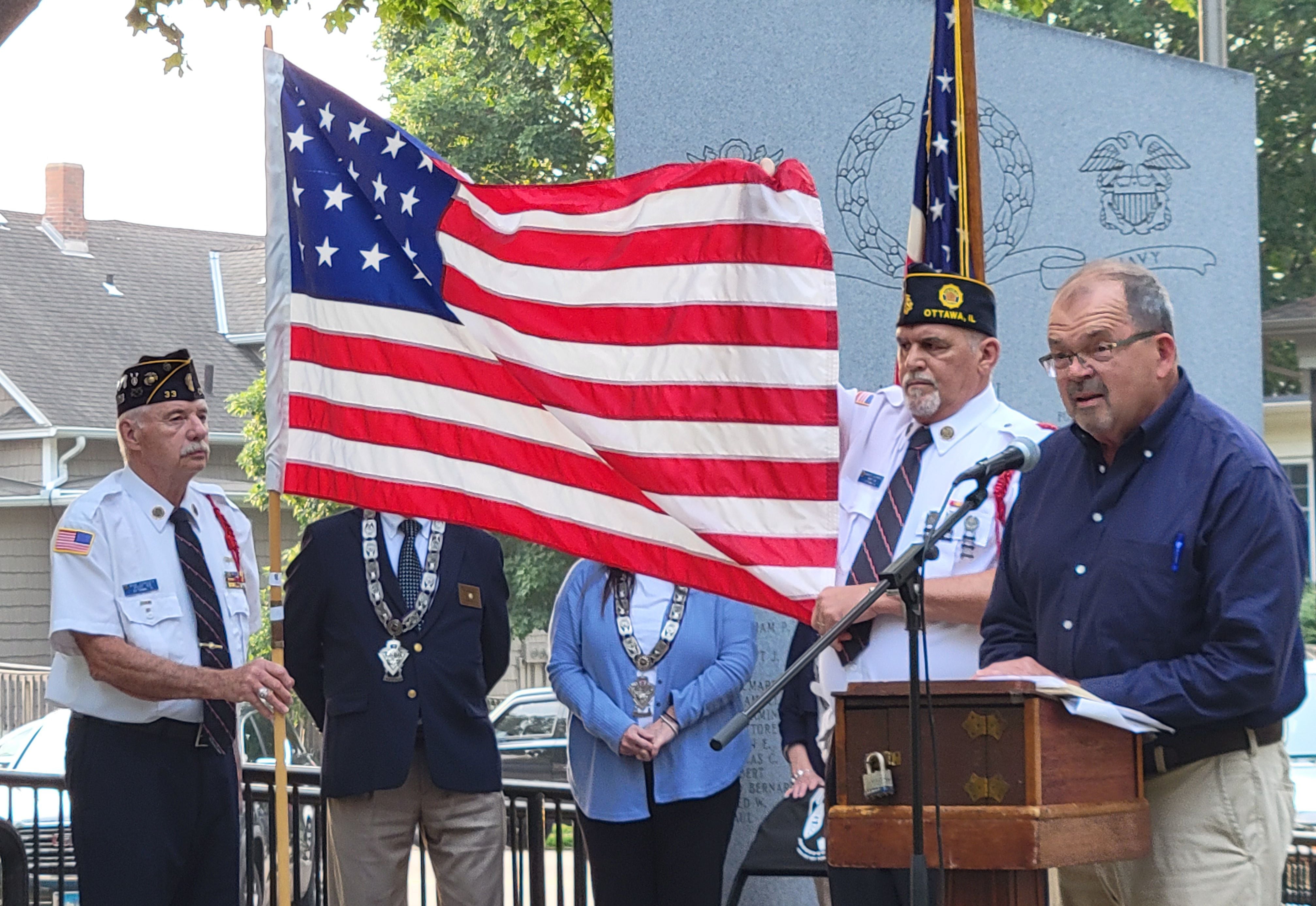 While members of the Ottawa American Legion Post 33 display a historic version of the American flag, former Mayor Bob Eschbach reads the story of that flag to the crowd at Flag Day ceremonies Wednesday, June 14, 2023, at Washington Square.