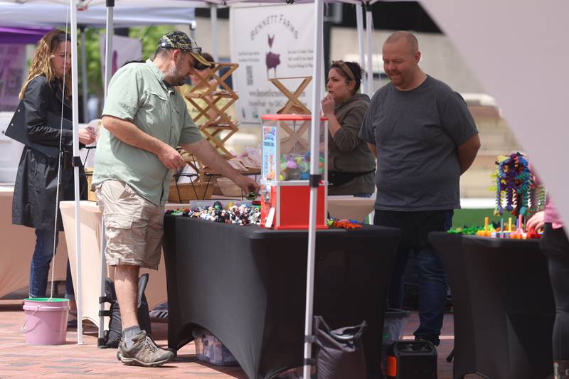 A person browses on of dozen tents set up at the new city square for the farmers market on Friday, May 22, 2026 in Joliet.
