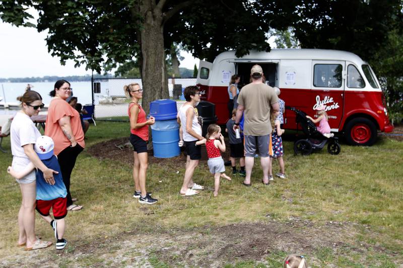 People lineup to buy frozen custard from the Julie Ann’s Frozen Custard truck during the Crystal Lake Park District and Public Library's Summer Singalong for Kids on on Friday, June 21, 2024, at Crystal Lake's Main Beach.