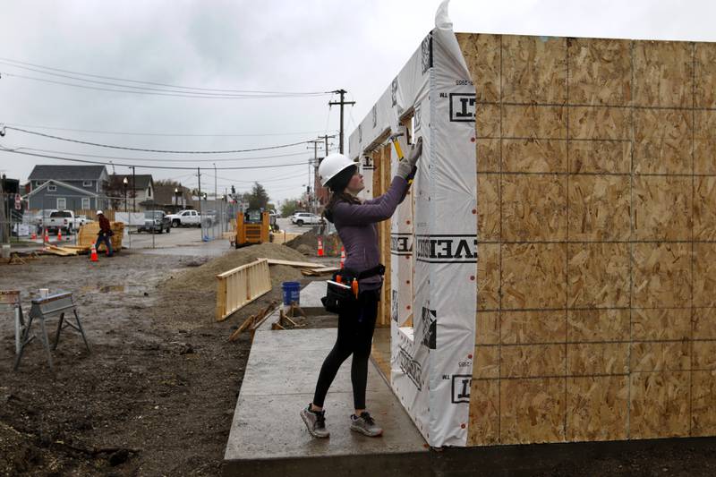 McHenry High School student Kilynn Axelson installs weather wrap on a tiny shop being constructed Monday, May 1, 2023, at the new McHenry Riverwalk Shoppes at Miller Point Park in McHenry. McHenry High School students joined volunteers from Habitat for Humanity, McHenry Parks and Recreation Department, and contractors to build the shops at the site.