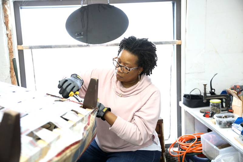 Jesseca Watson strips the old uphostery from a chair at Valley Upholstery and Design in Batavia. Following the September 2021 death of Valley Upholstery and Design owner Jesse Pitts, his family and friends, including daughter Jesseca Watson, wife Eloise and friend Ruth Scott, have been working dilligently to complete his customers’ projects and keep the shop open.