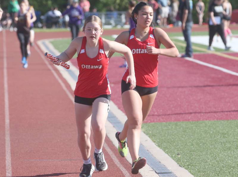Ottawa's Ailey Harstad takes off with the baton from teammate Hailey Martin in the 4x800 relay during the Interstate 8 Conference girls track championship on Friday, May 9, 2025 at Morris High School.