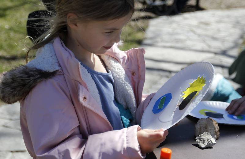 Anna Deutsh, 7, of Woodstock, plays with an eclipse plate craft she made on Monday, April 8, 2024, at the Crystal Lake Park District's Nature Center.