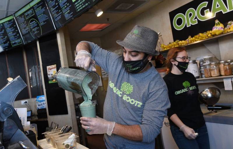 Umar Ahmad, owner of Organic Rootz health food store in Barrington, makes a Maaz's MYLK smoothie Thursday afternoon. The smoothie has fruit, nuts, spices and local honey.