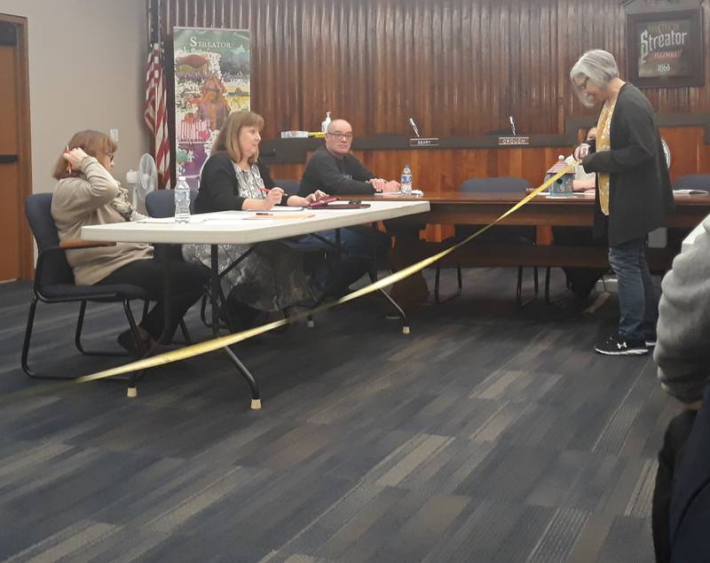 Michelle Proksa holds one end of a tape measure and Sandy Austin holds another end (out of the picture frame) to demonstrate how far 20 feet is to the Streator City Council on Tuesday, March 7, 2023. They said it's closer than they were comfortable allowing chickens roam near their properties.