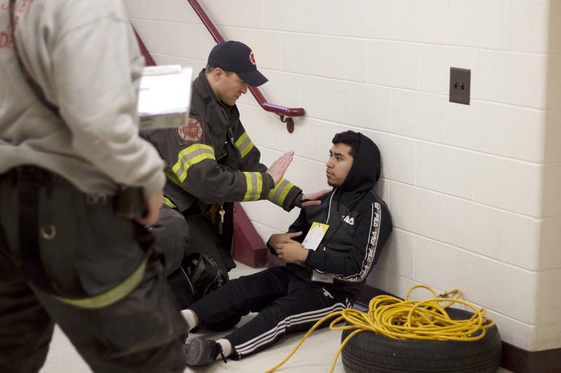 A firefighter performing a medical evaluation of a student actor inside Joliet West High School on Tuesday, March 25, 2025, for a staged emergency drill simulating the aftermath of a gas explosion.