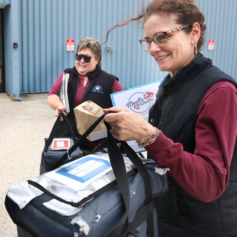 Volunteers Stephanie Barring (left) and Chris Sauter, both from DeKalb, load up their vehicle with a Meals on Wheels delivery to distribute Tuesday, April 23, 2024, at the Voluntary Action Center in Sycamore. VAC is celebrating its 50th anniversary this year.