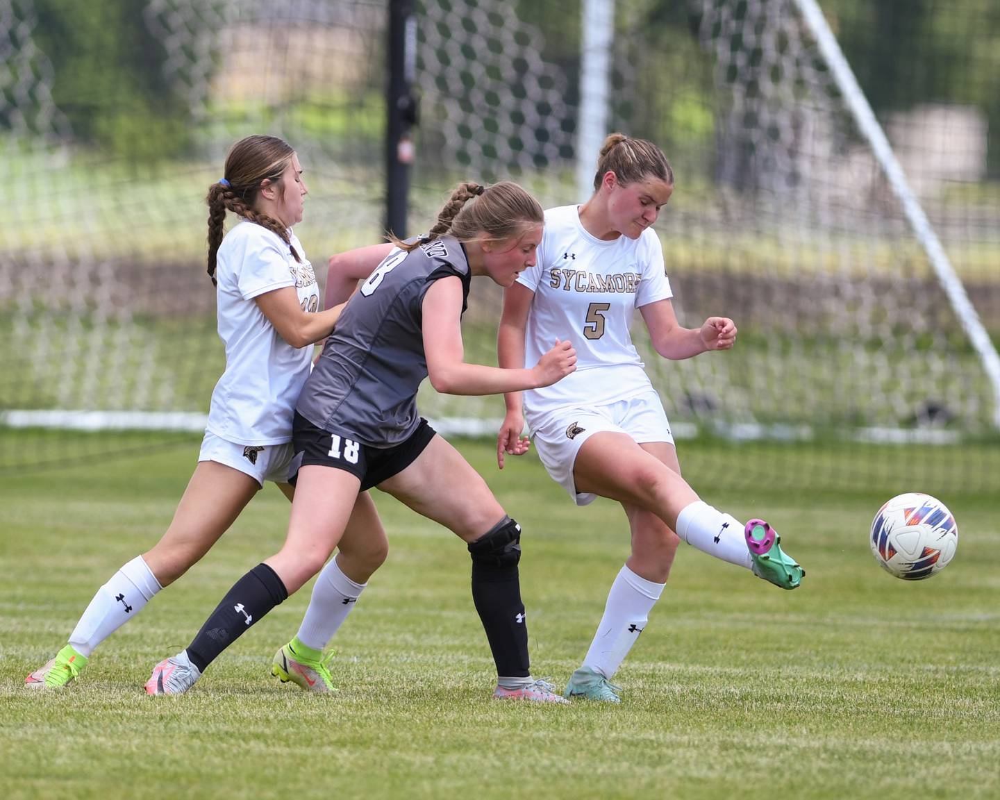 Sycamore's Grace Amptmann (5) helps clear the goal as teammate Faith Schroeder, left, helps defend off Kaneland's Mallory Nitsche (18) during the regional title game on Saturday May 18, 2024, held at Kaneland High School.