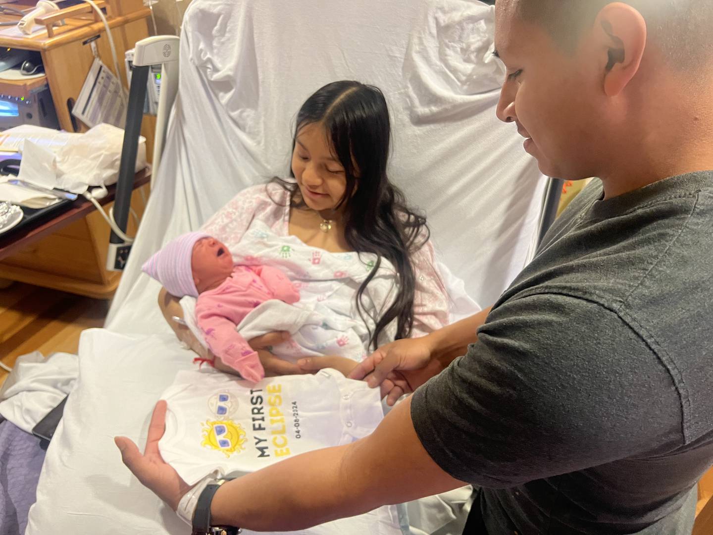 (From left) Arlinuelia’s daughter Leslie arrived at 11:49 a.m. on Monday, April 8, 2024, at Northwestern Medicine Kishwaukee Hospital in DeKalb, the day of the solar eclipse. Hospital nurses gifted the parents with a special eclipse onesie to mark the occasion.