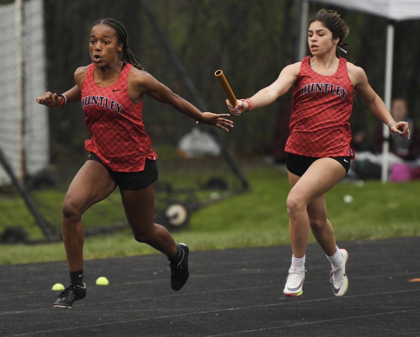 Huntley’s Victoria Evtimov hands the baton to teammate Alex Johnson in the 4x100-meter relay at the Wheaton Warrenville South girls track invitational in Wheaton on Friday, April 29, 2022.