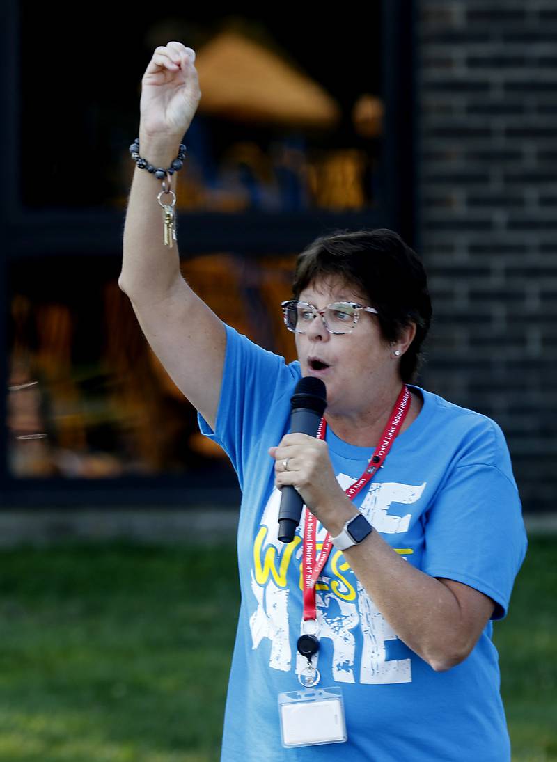Principal Beth Klinsky raises her hand to signal for students to quiet down on the first day of school at West Elementary School in Crystal Lake on Wednesday, Aug. 16, 2023.