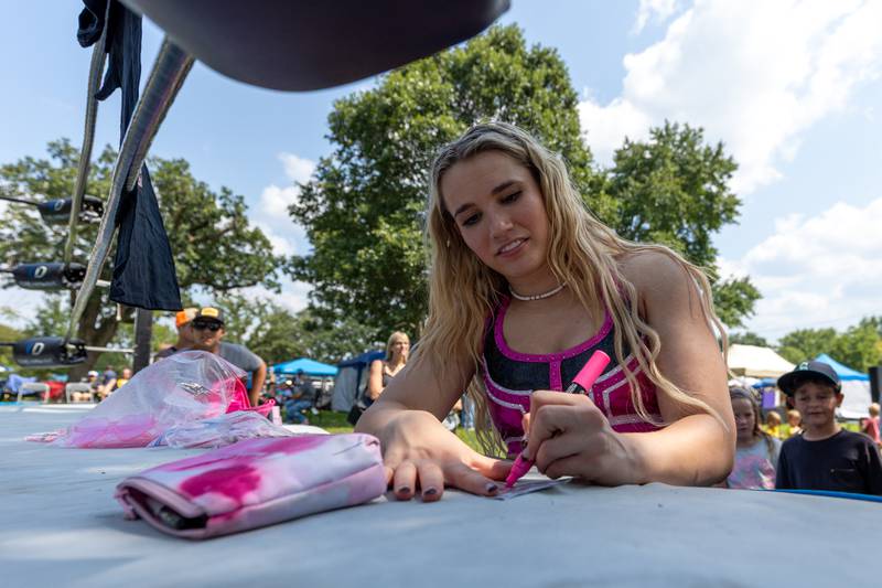 Brittnie Brooks signs $100 dollar bill at the Taste of the Illinois Valley DreamWave Wrestling event on Saturday, August 2, 2025 at Centennial Park in Peru.