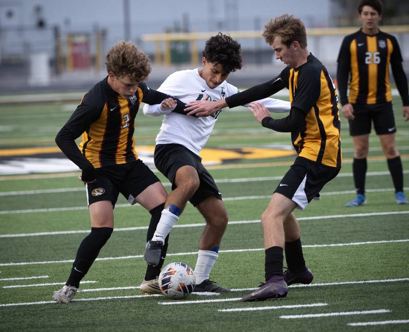 Herscher's Jacob Benoit, left, and Rowan Keigher, right, take the ball from Bishop McNamara's Diego Perez, center, in a regional match-up on Tuesday, October 21, 2025.