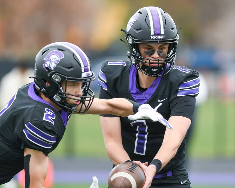 Downers Grove North's Owen Lansu (1) hands the ball off to teammate Downers Grove North's Alec Fiermuga (2) during the class 7A game on Saturday Nov. 9, 2024, while taking on Fenwick High School held at Downers Grove North High School.