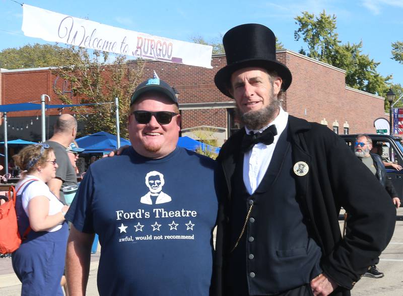 Cory Leefers of Springfield wares his Fords Theatre shirt while posing next to Abraham Lincoln portrayed by Kevin Wood of Adrian Mich. during the 55th annual Burgoo Festival on Sunday, Oct. 12, 2025 in Utica.