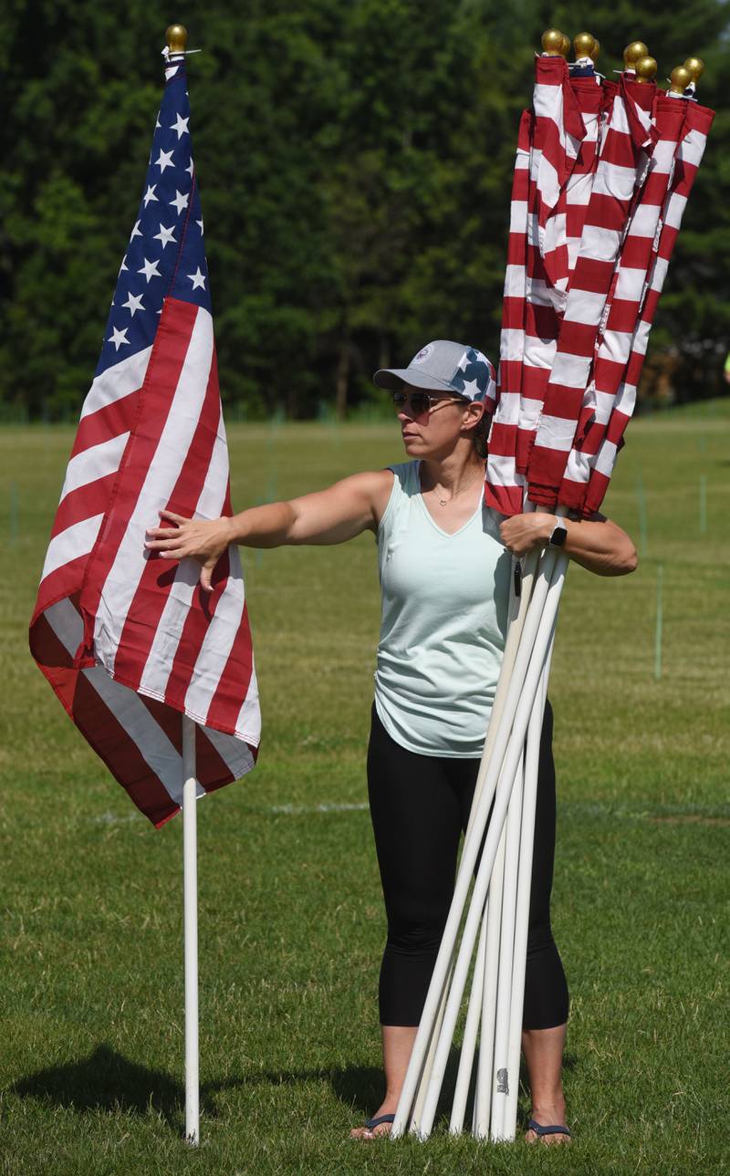 Erika O’Malley of Wheaton places flags during setup for the Wheaton Field of Honor at Seven Gables Park on Saturday, June 28, 2025.
