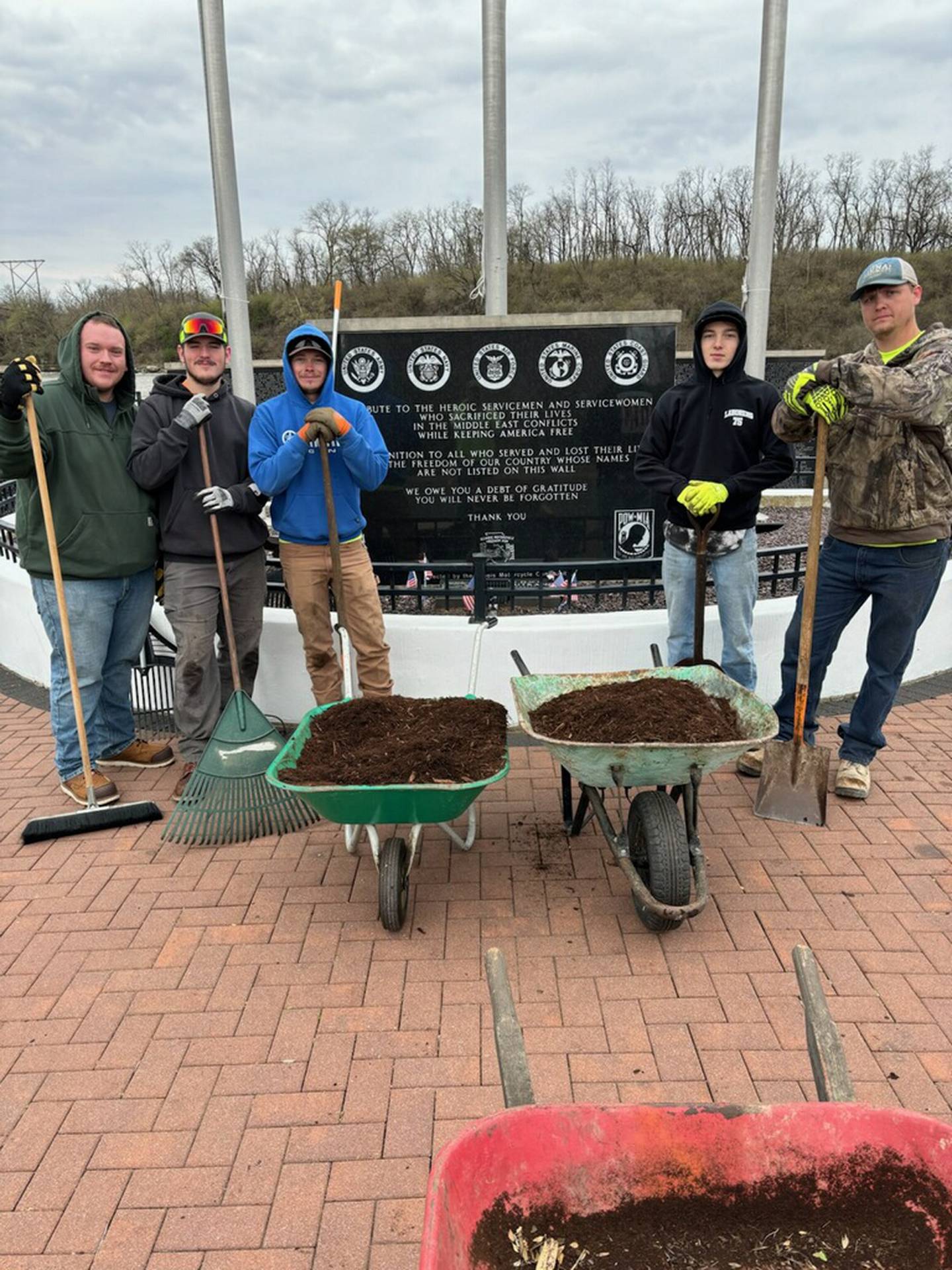 Laborers Local 393 volunteers (from left) Zack Smith, Dustin Gerkitz, Kyle Mesarchik, Brayden Cain and Trent Miskell help with spring beautification at the Middle East Conflicts Wall Memorial in Marseilles. The mulch was donated by Midwest Trading of Ottawa and flowers were donated by Janus Gardens of Marseilles.