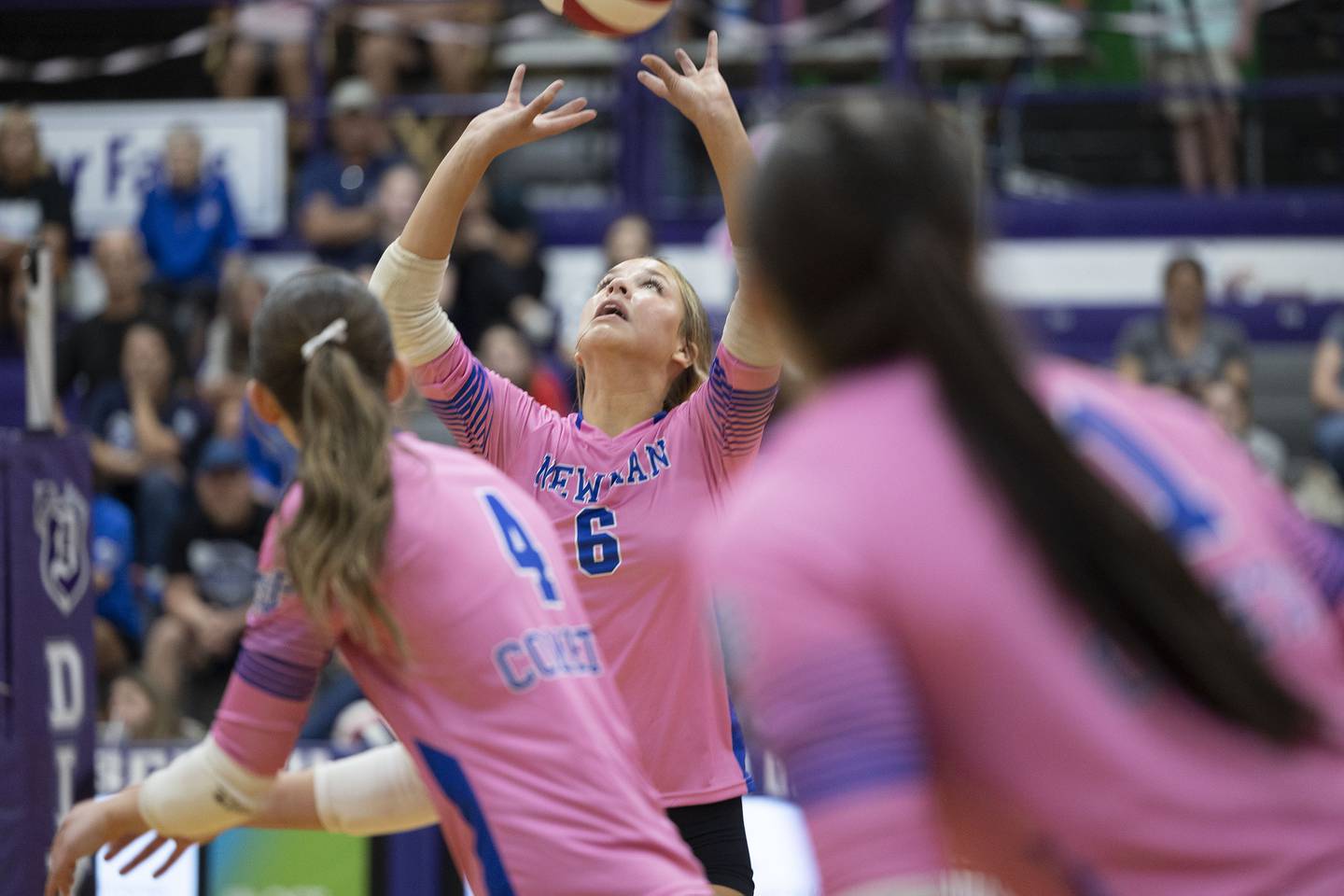 Newman’s Brooklyn Smith sets the ball as Ruby Burger and Bella Lanning look on against Dixon Thursday, Oct. 2, 2025.