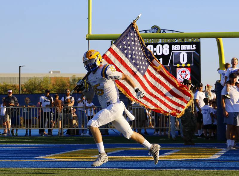 Lyons Township's Cooper King runs in the American flag during the boys varsity football game between Hinsdale Central and Lyons Township on Friday, Sept. 9, 2022 in Western Springs, IL.