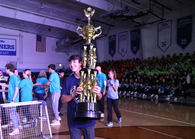 Nazareth Academy student Luke Holstrom carries a giant trophy his student/facutly team won in an Olympics-style competition during a homecoming pep rally at the La Grange Park school on Friday, Sept. 29, 2023.