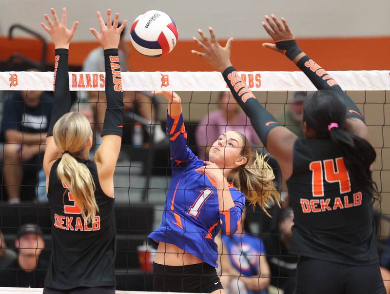 Genoa-Kingston's Presley Meyer spikes the ball between DeKalb's Meila Robinson (left) and Jordan Grant during their match Wednesday, Sept. 10, 2025, at DeKalb High School.
