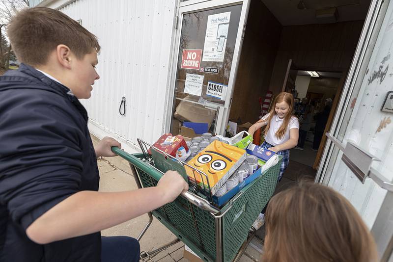 St. Anne’s students work to maneuver a heavy cart of food items into the Dixon Food Pantry Friday, Nov. 21, 2025. The school was divided into houses to see who could generate the most donations. The winning house got to deliver the items and get a tour of the facility.