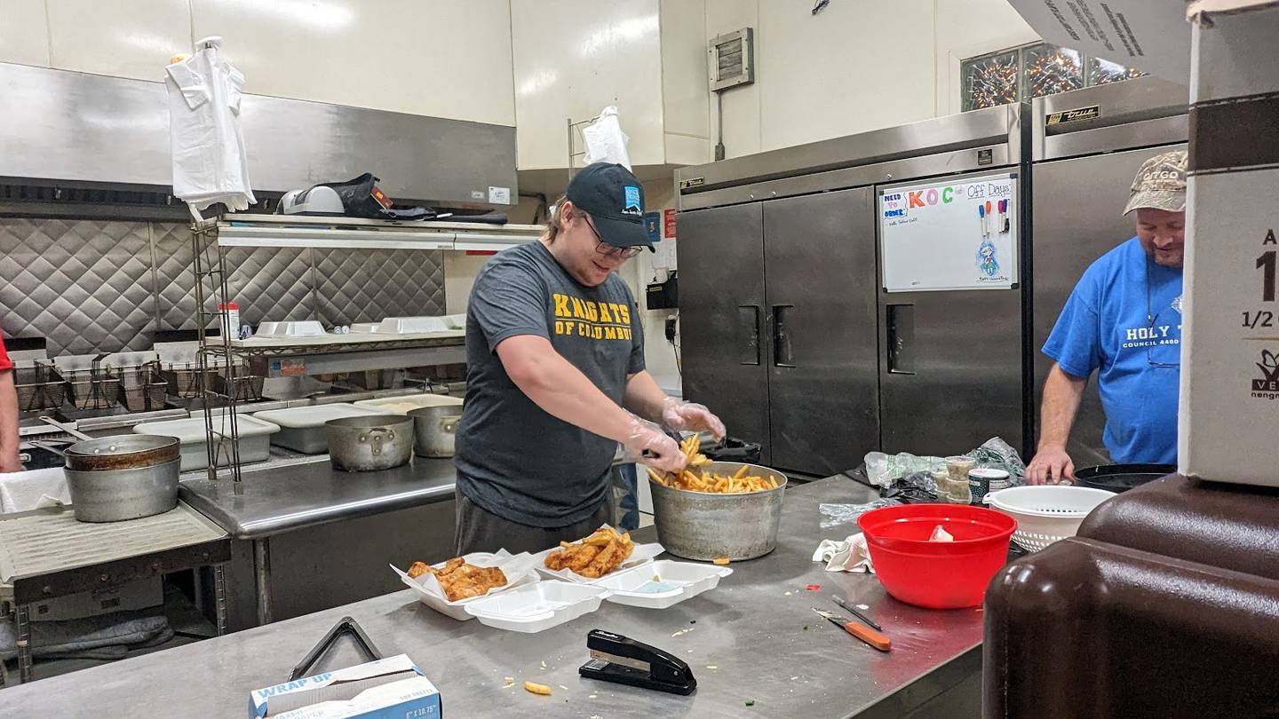 Andrew Ardaugh gets two fish dinners ready for carryout on Friday, Feb. 17, 2023, at the Knights of Columbus Holy Trinity Council #4400 in Joliet. His father Phil Ardaugh, council treasurer, works beside him. The Knights of Columbus Holy Trinity Council #4400 hosts a fish fry on Fridays and Saturdays all through the year.