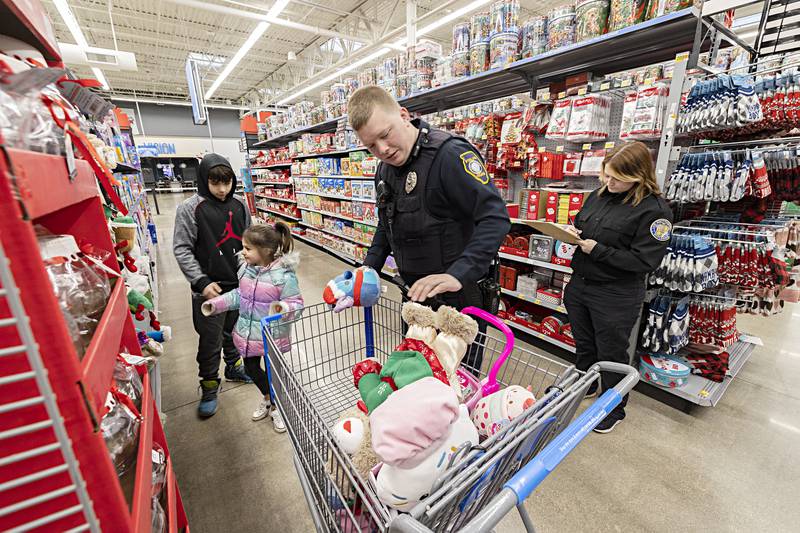 Officer Travis Ganther and police explorer Emma Youngquist help Zamorah Fordham and Steven Fordham pick out gifts Saturday, Dec. 9, 2023.