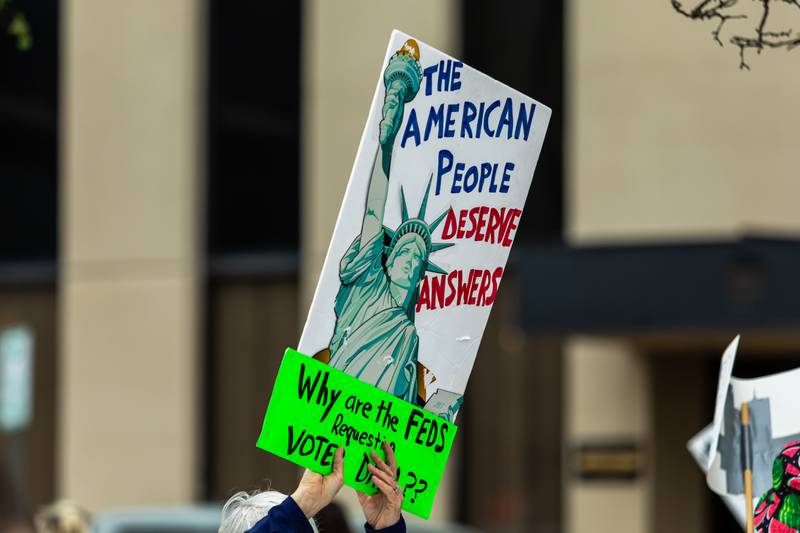 An attendee holds up a sign at the Good Trouble Lives On event in Downtown Joliet on July 17, 2025.