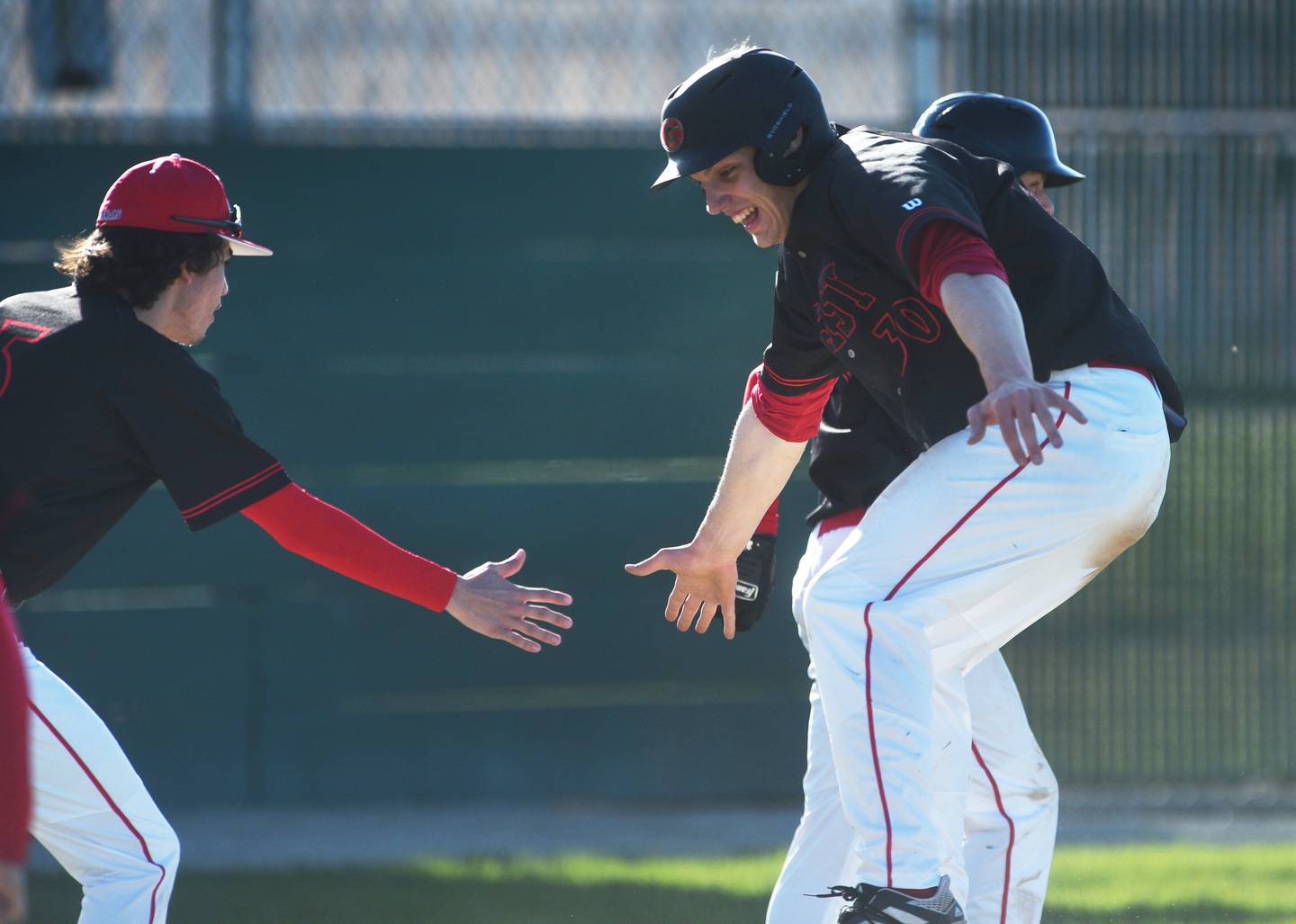 Glenbard East's Eddie Vercruysee (30) scores on a base hit and kids kudos from teammate Colin Murphy during during Thursday's baseball game against Bartlett.