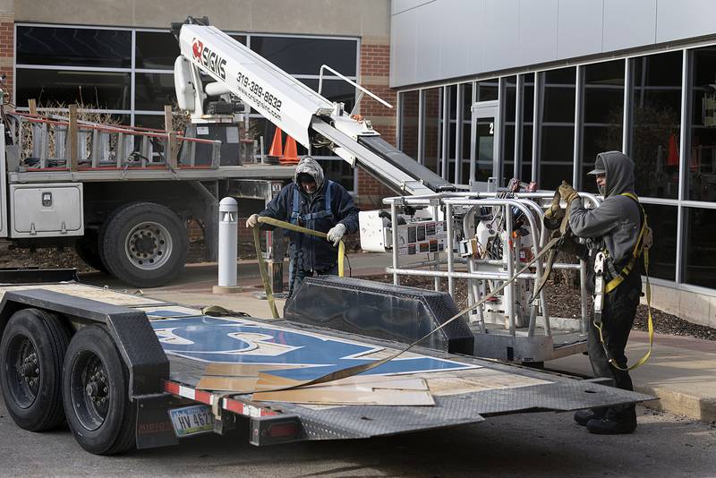 Scott Coots (left) and Alex Hartman of CR Signs of Cedar Rapids, strap down a section of the former KSB Hospital sign Friday, Dec. 13, 2024, in Dixon. The hospital will be rebranded OSF Saint Katharine Medical Center.