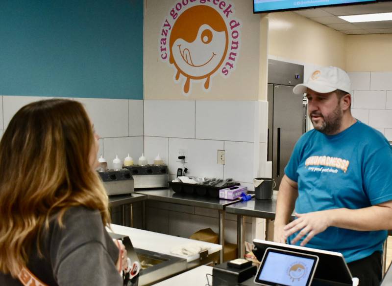 Nick Boulougouris, owner of Lukumadness!, talks with first-time customer Justine Evett. Boulougouris opened the Downers Grove doughnut shop recently after being inspired while on a trip to Iceland.