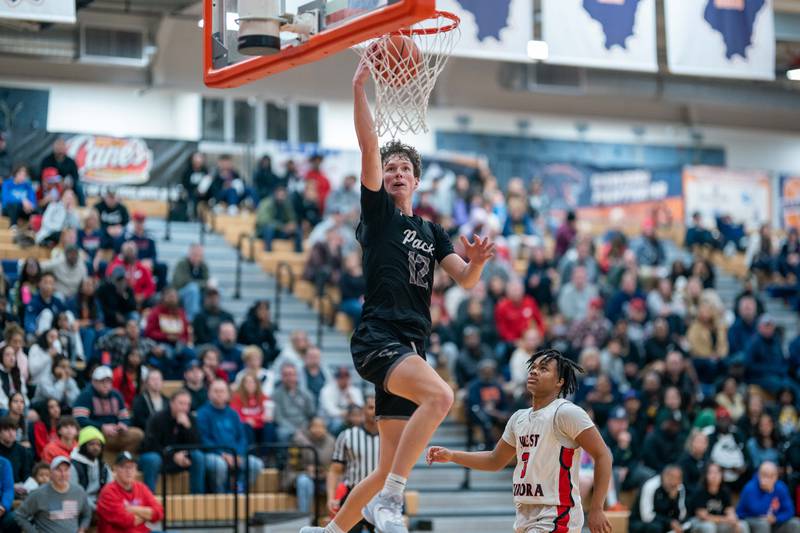 Oswego East's Ryan Johnson (12) drives to the basket against West Aurora's Datavion McClain (3) during the hoops for healing basketball tournament at Oswego High School on Friday, Nov 25, 2022.