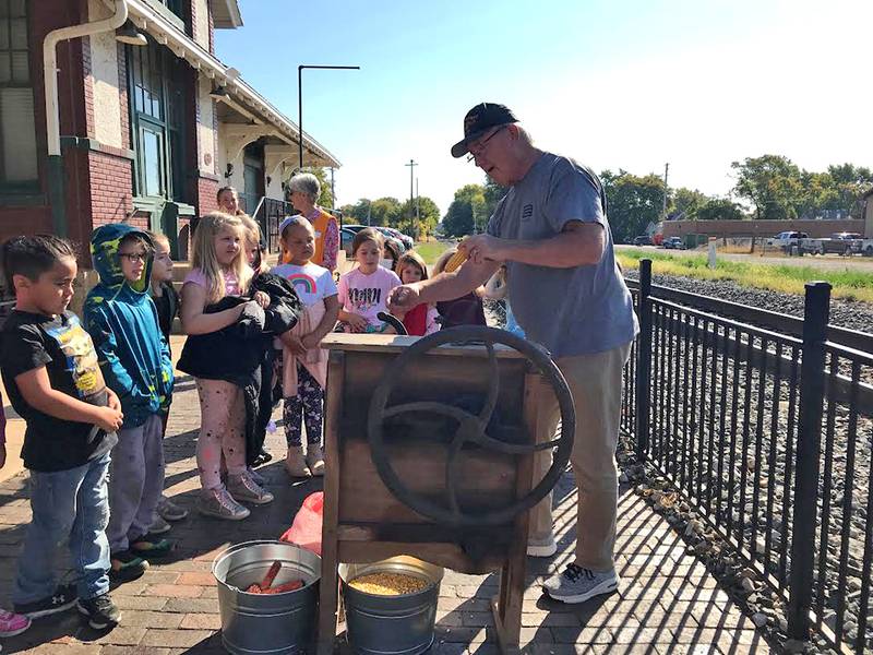 John Smith provides a corn sheller demonstration to Marseilles Elementary School second-graders on Oct. 6 and teachers students about the different types of corn grown in Illinois.