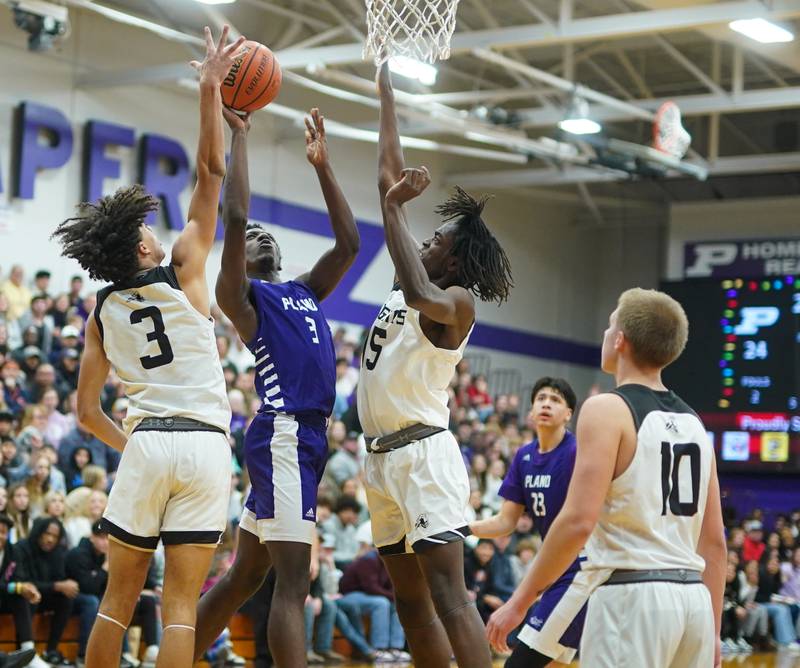 Plano’s Christ Keleba (3) shoots the ball in the paint against Kaneland's Evan Frieders (3) and Freddy Hassan (15)during a championship game of the 60th annual Plano Christmas Classic Basketball Tournament at Plano High School on Saturday, Dec 30, 2023.