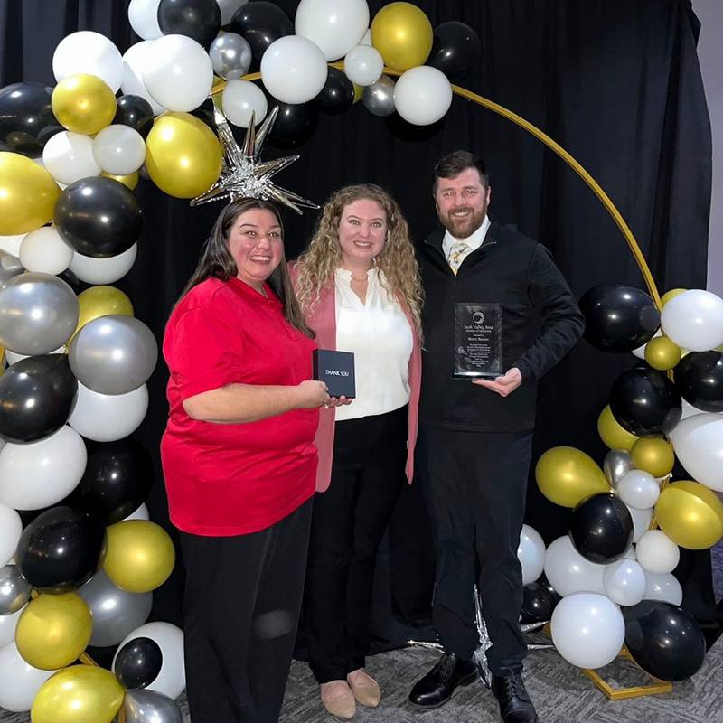 Dallas Knack (center) presents the Ambassador of the Year Award to Tygen Bausman (left) and the 2024 Chamber Champion Award to Brent Reuter (right).
