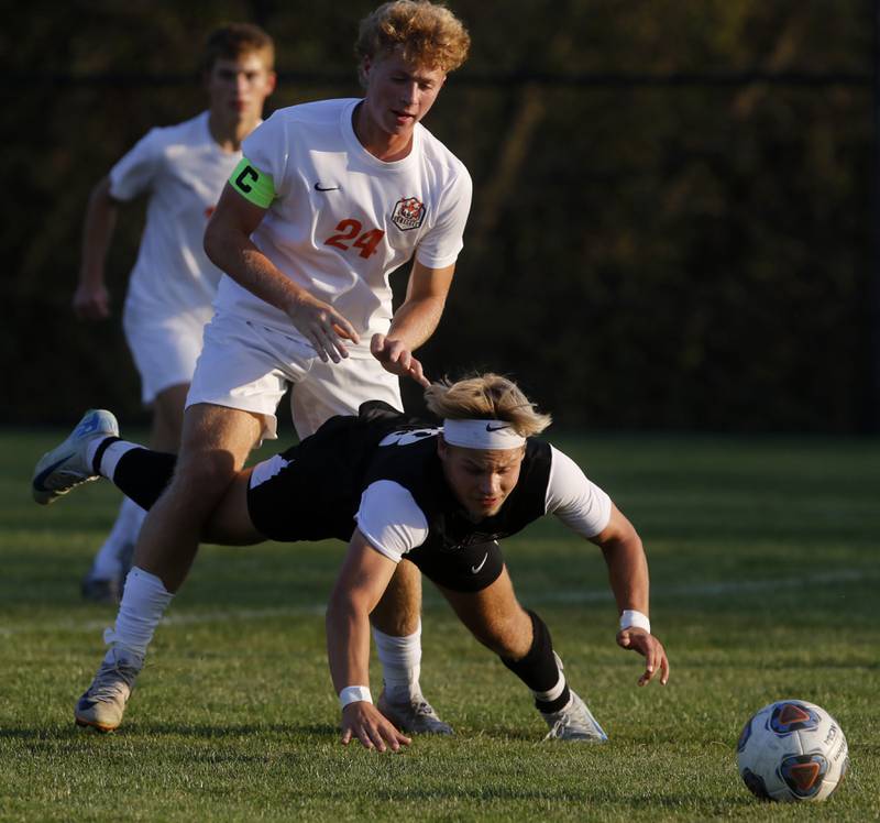 Prairie Ridge's Gabriel Porter falls to the ground while battling for control of the ball with \clc24\ during a Fox Valley Conference soccer match on Thursday, Oct. 10, 2024, at Prairie Ridge High School.