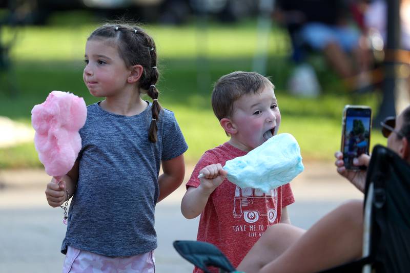 Charlie Elliott, 4, right, takes a big bite of his cotton candy next to his sister, Nora, 7, both of Momence, during the 87th Momence Gladiolus Festival Main Street Parade on Friday, Aug. 8, 2025.
