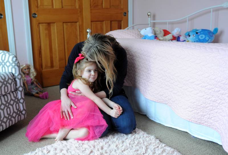 Everly Backe, 4, who has had multiple open heart surgeries to correct congenital heart defects, snuggles Friday, Feb. 11, 2022, with her mother, Lauren, in their Crystal Lake home. As Everly has became more aware of her chest scar, which they call her "zipper," her dad, Matt, recently decided to get a tattoo that matches his daughter’s scar from her surgeries so she does not feel alone in having the scar.