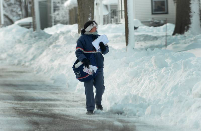 USPS postal worker Val Villarreal walks down Lincoln Street in Mt. Morris on Saturday, Jan. 13, 2024 delivering mail because the sidewalk along the north side of the street was not shoveled.. Friday's winter storm dumped 10-12 inches of snow on the village with strong winds, more snow, and zub-zero temperatures forecasted into Sunday.