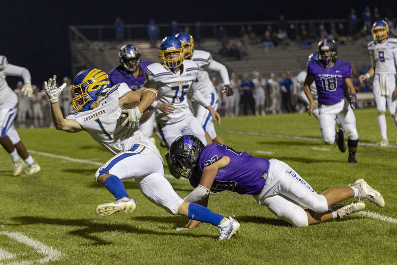 Johnsburg running back Jake Metze (1) runs past the diving attempt of Plano defender Aydan Olson (27) during Friday's game in Plano.