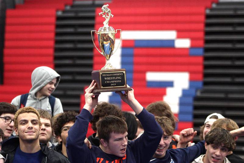 McHenry’s Chris Moore hoists the Fox Valley Conference championship trophy after the Warriors clinched an outright title with a win over Dundee-Crown in varsity wrestling at Carpentersville Thursday night.
