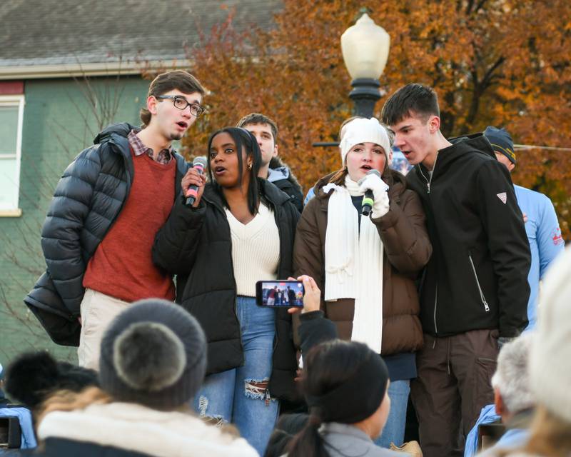 Members of the Downers Grove North choir sings the National anthem at the start of the Grove Express 5k race held in downtown Downers Grove on Thursday Nov 23, 2023.