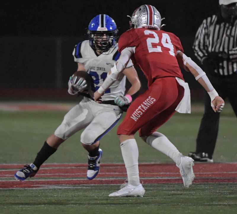 Lake Zurich’s Chris Pirrone looks for room against Mundelein’s Maddux Hermestroff in a football game in Mundelein on Friday, October 13, 2023.