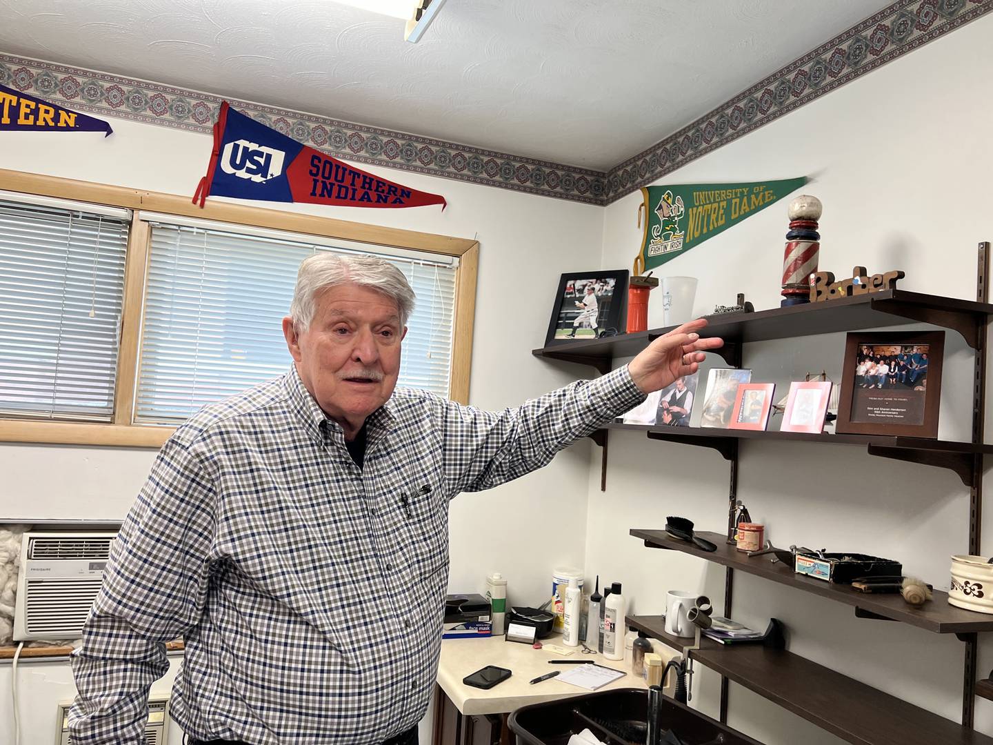 Don Henderson, 88, points at a barber pole he was gifted for his barbershop, Spartan Style, on April 17, 2025. Henderson first learned to cut hair in 1957, while Dwight D Eisenhower was President.