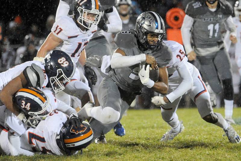 Oswego East quarterback Tre Jones (9) gains some tough yards against the Oswego defense during a varsity football game at Oswego East High School on Friday, Oct. 14, 2022.